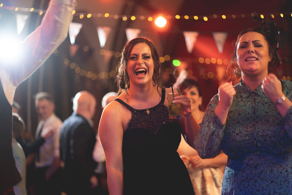 Guests enjoying and celebrating at an evening party with stage lighting in the background.