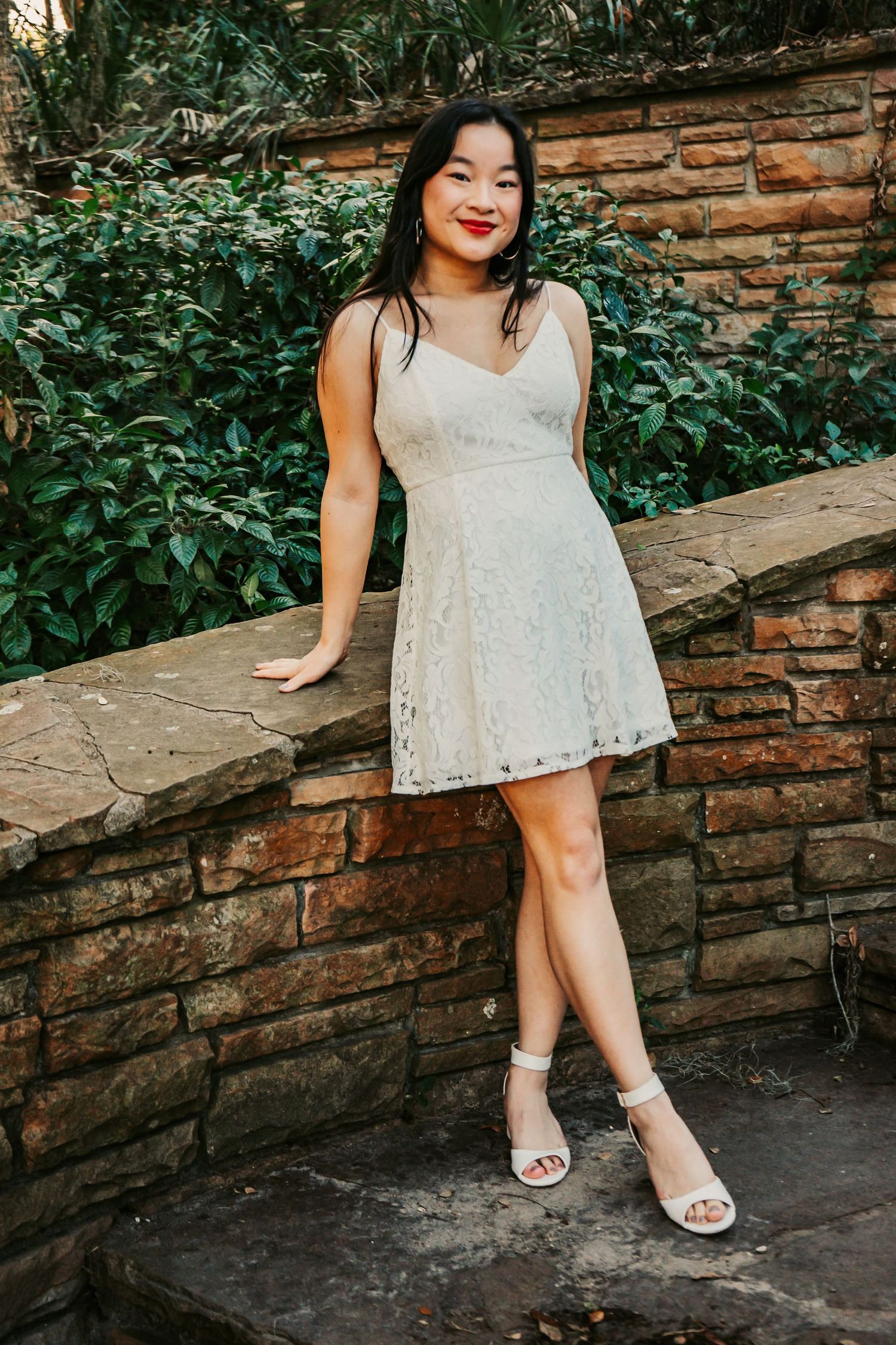 Senior portrait at Philippe Park in Pinellas County - graduate in lace dress in front of stone and greenery
