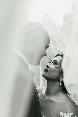 Romantic black and white portrait of a couple under a wedding veil.