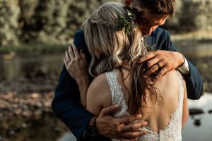 An intimate wedding moment captured near a waterfront with natural lighting.