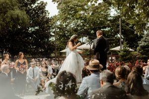 An outdoor wedding ceremony with guests watching the couple share a dance moment on an elevated platform.