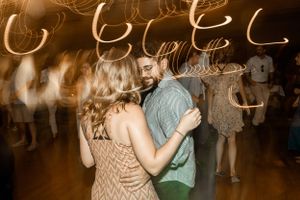 Couples dancing under warm glowing lights at an evening celebration.