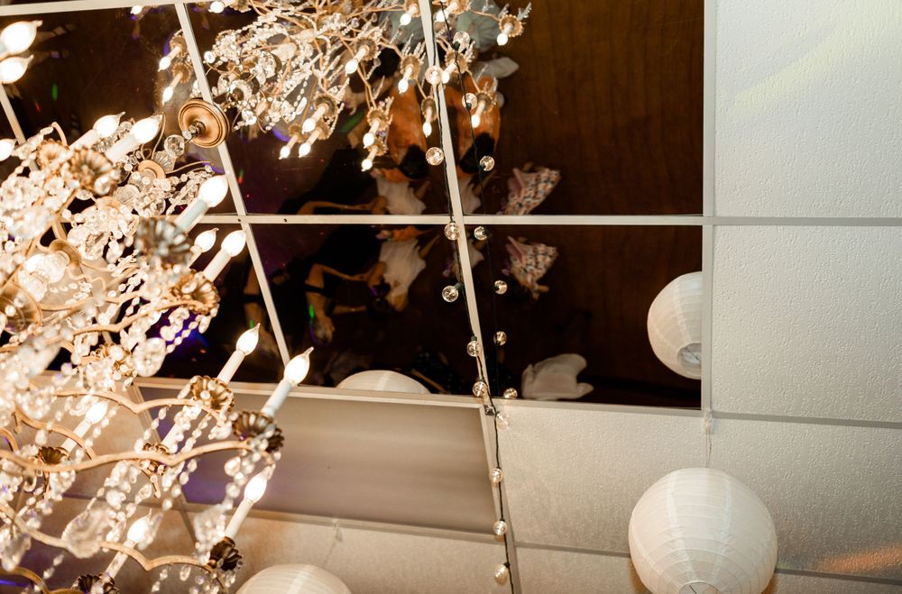 White paper lanterns and crystal chandeliers create elegant ceiling decor at an indoor venue.