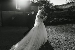 A dramatic backlit black and white photo of a couple in wedding attire at sunset.