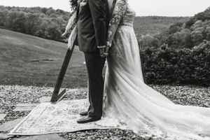 A romantic black and white wedding portrait featuring a couple standing on a decorative rug outdoors.