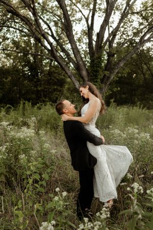 Romantic wedding photo of a couple embracing in a wildflower field at sunset.