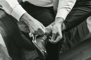 Close-up black and white shot of hands adjusting formal dress shoes.