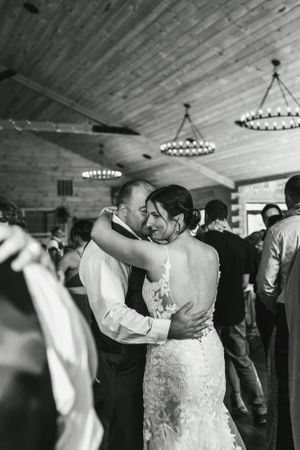 Intimate dance moment under rustic wood ceiling with chandelier lighting.