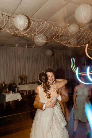 Wedding reception dance under paper lanterns and string lights with neon light trails in background.
