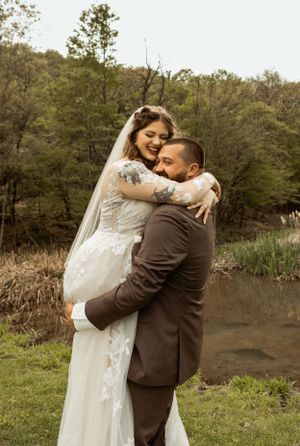 Joyful wedding couple embracing outdoors with natural scenery in background.