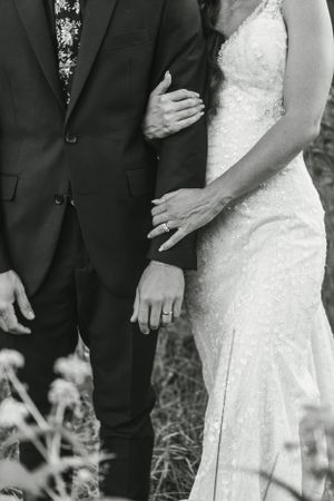 Black and white close-up of wedding couple showing lace dress detail and suit jacket.
