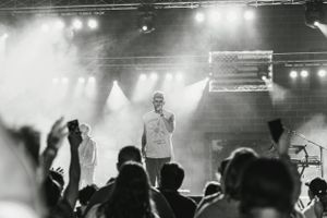 A silhouetted performer stands on stage with dramatic lighting and fog effects during a concert performance.
