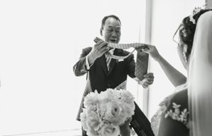 A candid moment during wedding preparations showing hands adjusting formal attire.