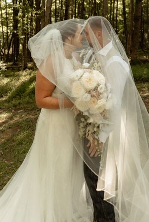 Romantic moment under a wedding veil with white and blush bridal bouquet.