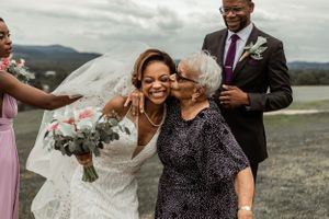 Joyful moment shared between wedding guests outdoors with mountains in background.