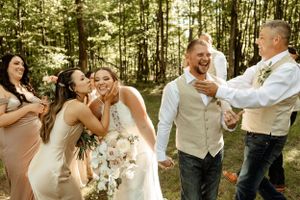 Joyful candid reactions during an outdoor forest wedding celebration.