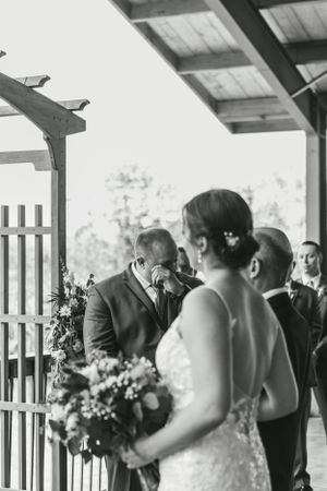 Black and white wedding ceremony photo showing emotional moment with floral bouquet.
