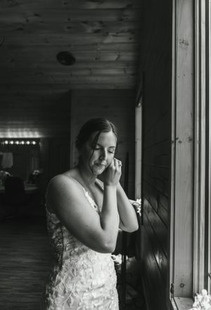Black and white portrait of person in lace dress near window creating emotional moment.