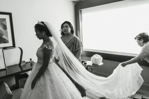 Wedding dress preparation scene with flowing veil and attendants helping the bride get ready.