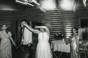 Dance party scene at a wedding reception with people moving across a dance floor beneath metallic decor.