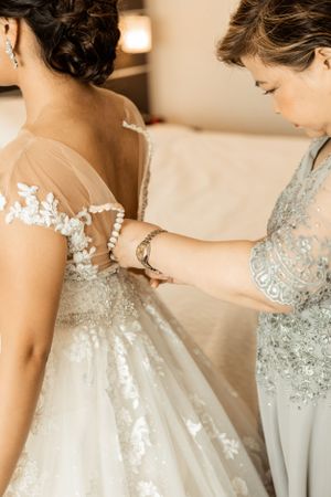 Close-up of delicate lace wedding dress buttons being fastened.