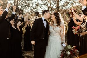 Wedding guests cheer and raise their hands as the newlyweds celebrate during an outdoor autumn ceremony.