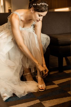 Close-up of formal dress and gold sandals being fastened.