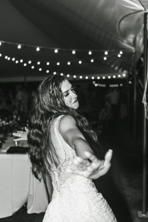 A joyful dance moment captured in black and white under string lights at a wedding reception.