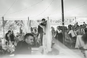 Black and white photo of wedding reception gathering under a tent with dancing guests.
