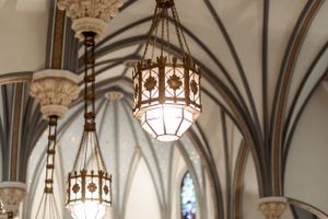 Ornate gothic ceiling architecture with hanging vintage lanterns in a church.