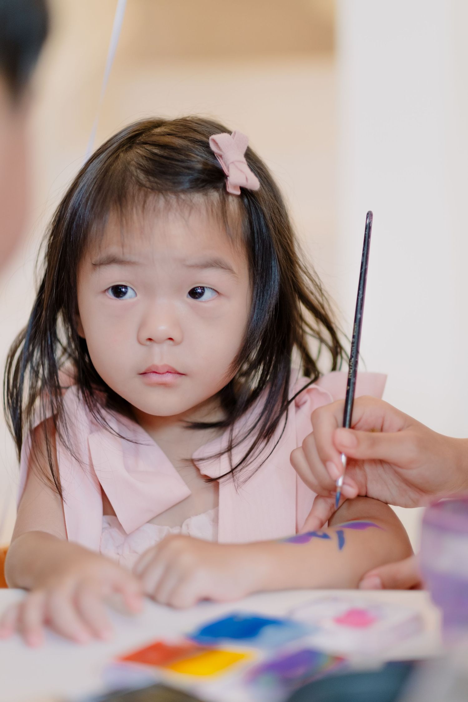 A young student holding a paintbrush works intently on an art project.
