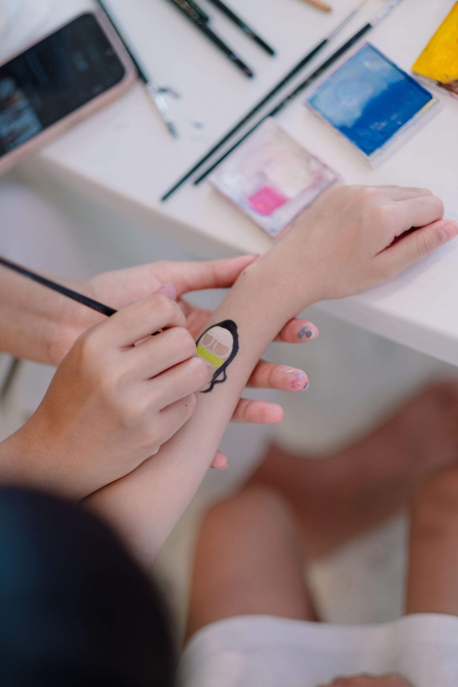 Close-up of hands applying face paint or temporary tattoo art.
