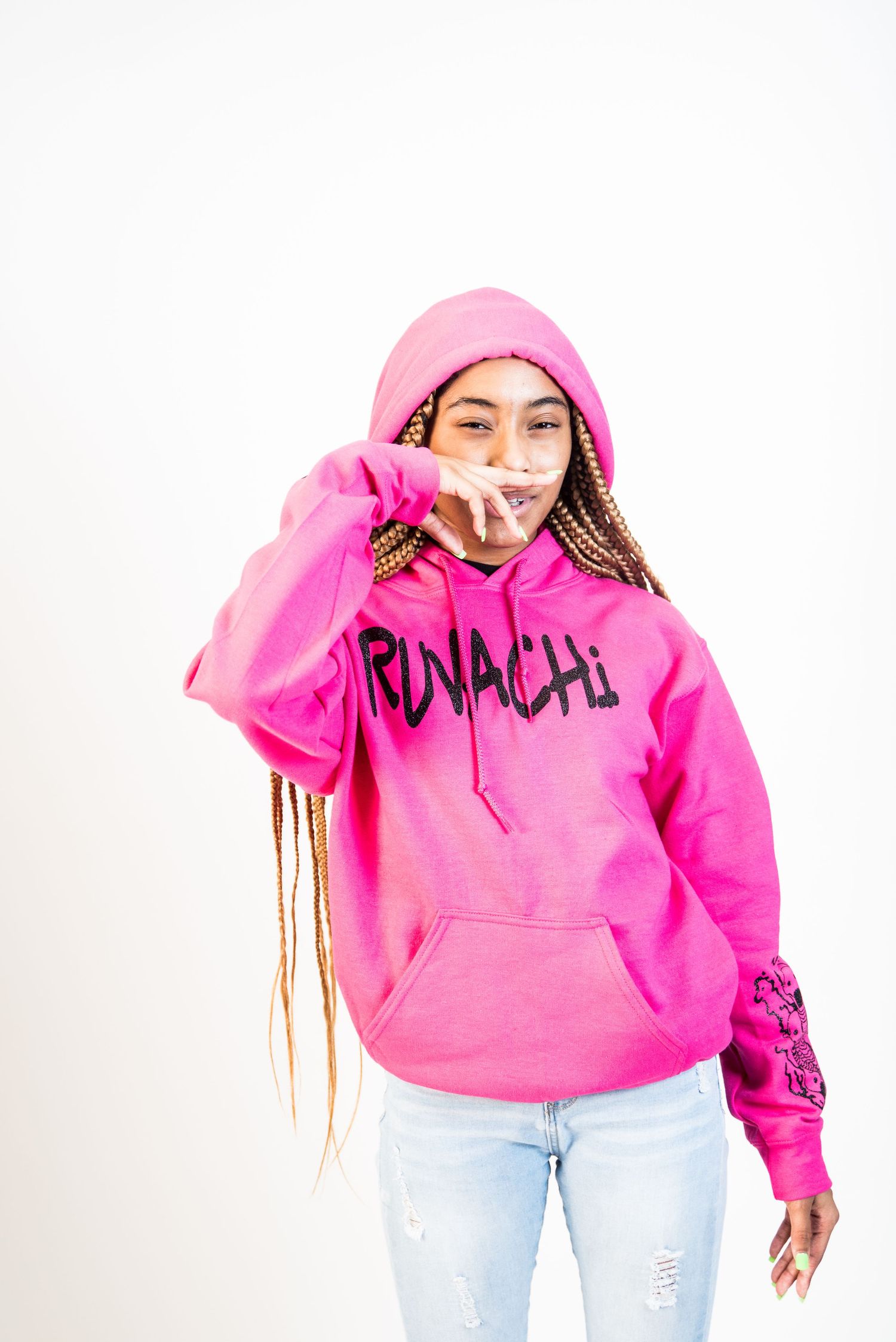 Studio photoshoot with bright pink hoodie and distressed jeans against white background.