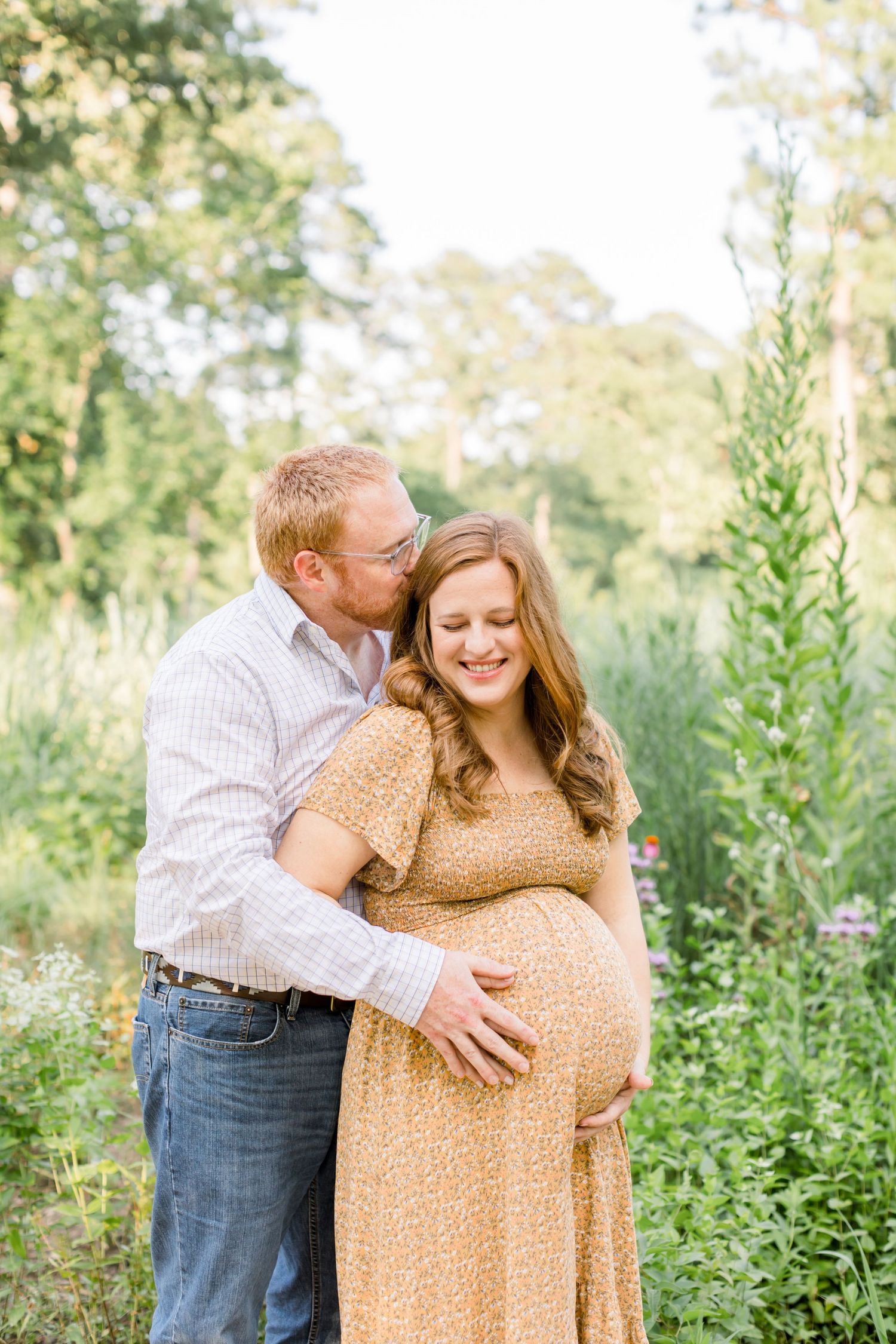 A couple embraces on a nature path with the person wearing a flowing tan dress.