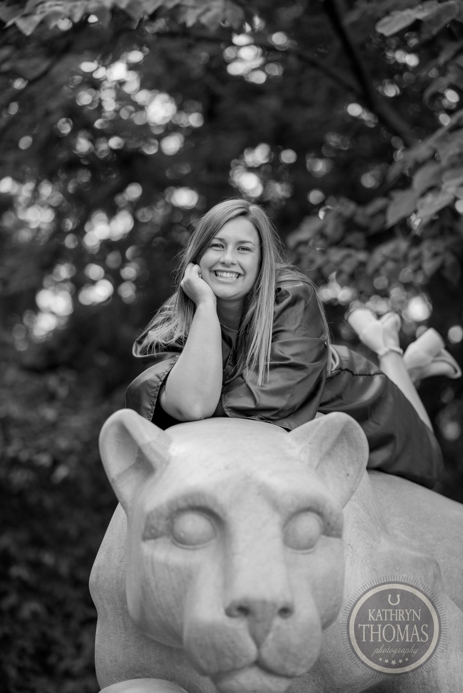 A black and white portrait taken on a stone lion statue with bokeh background effects.