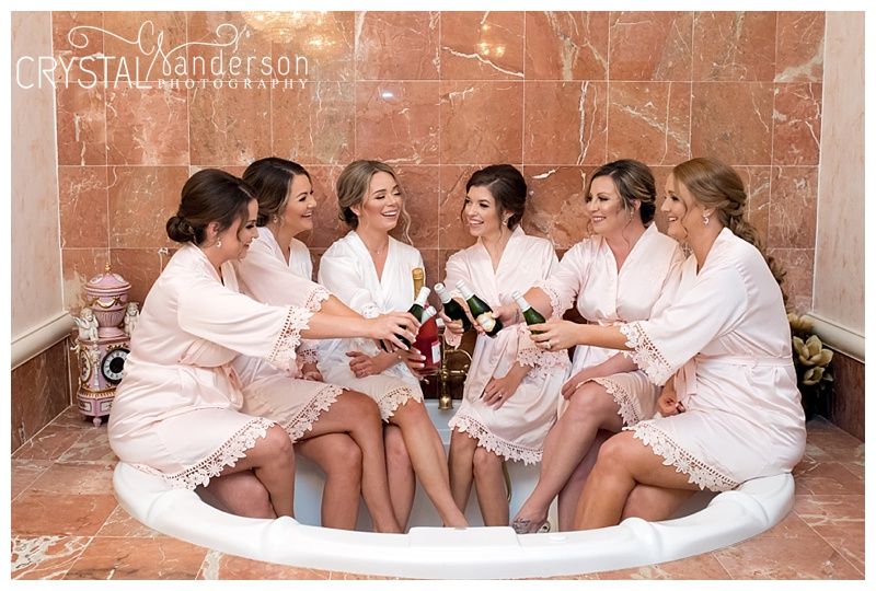 Group of women in white robes relaxing together before wedding ceremony.