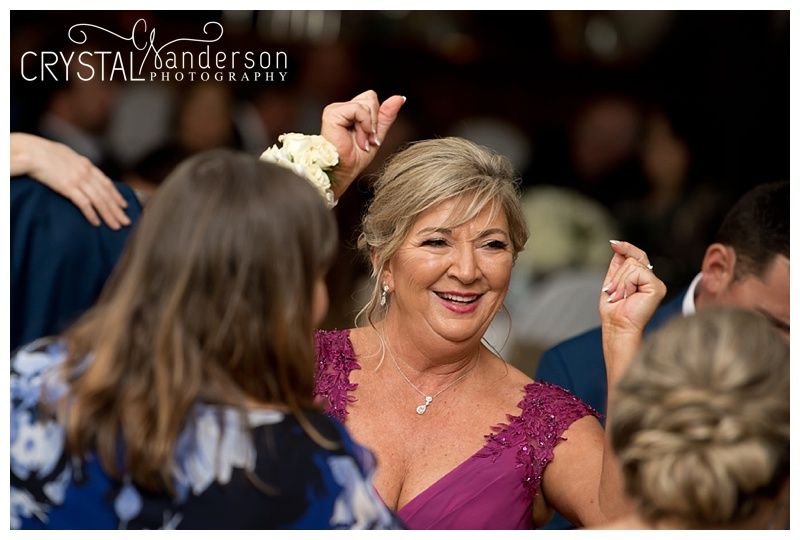 Wedding guests dancing and celebrating on a dimly lit dance floor at a reception.