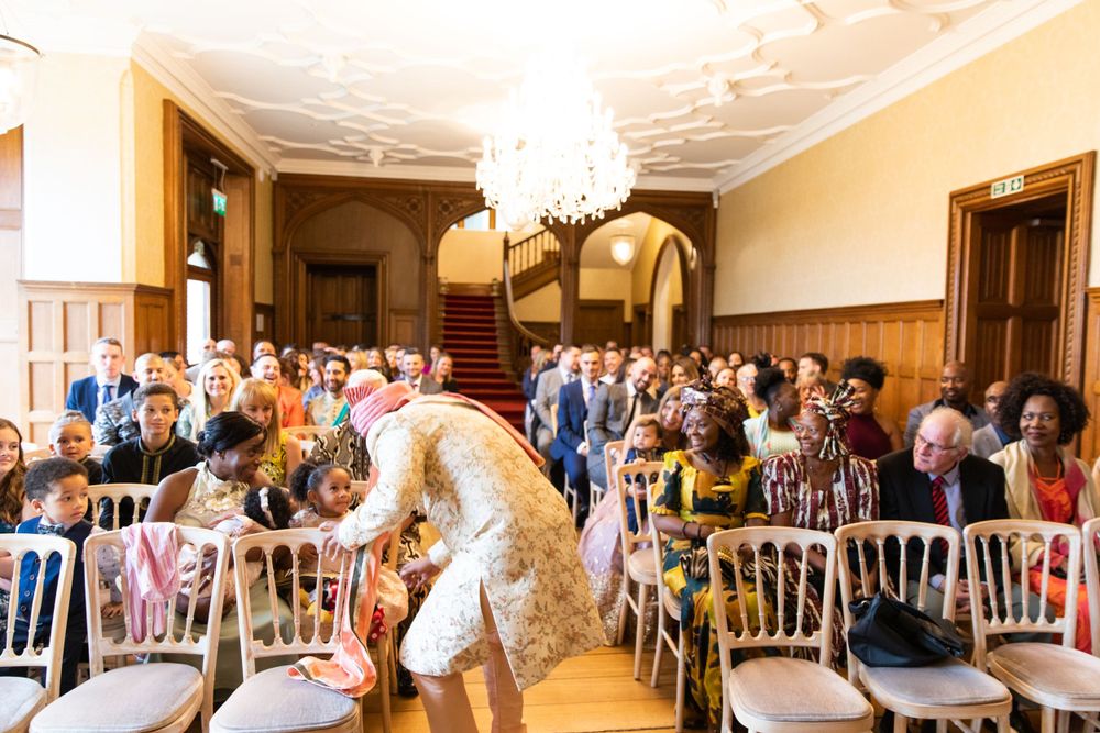 Wedding ceremony in progress in an elegant ballroom with chandelier and wooden details.