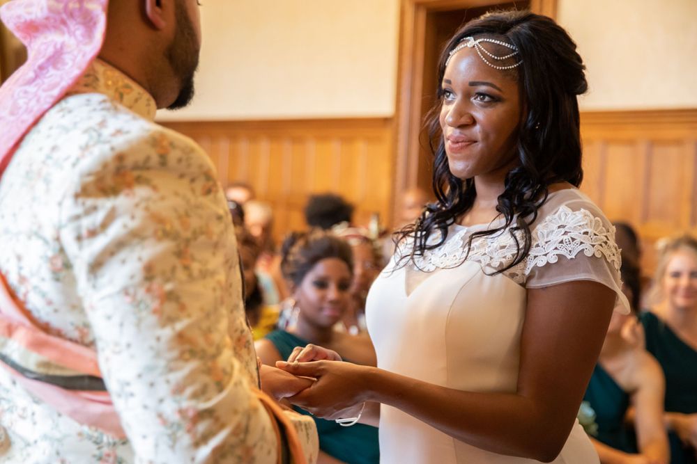 A couple shares a joyful exchange during their wedding ceremony in front of seated guests.