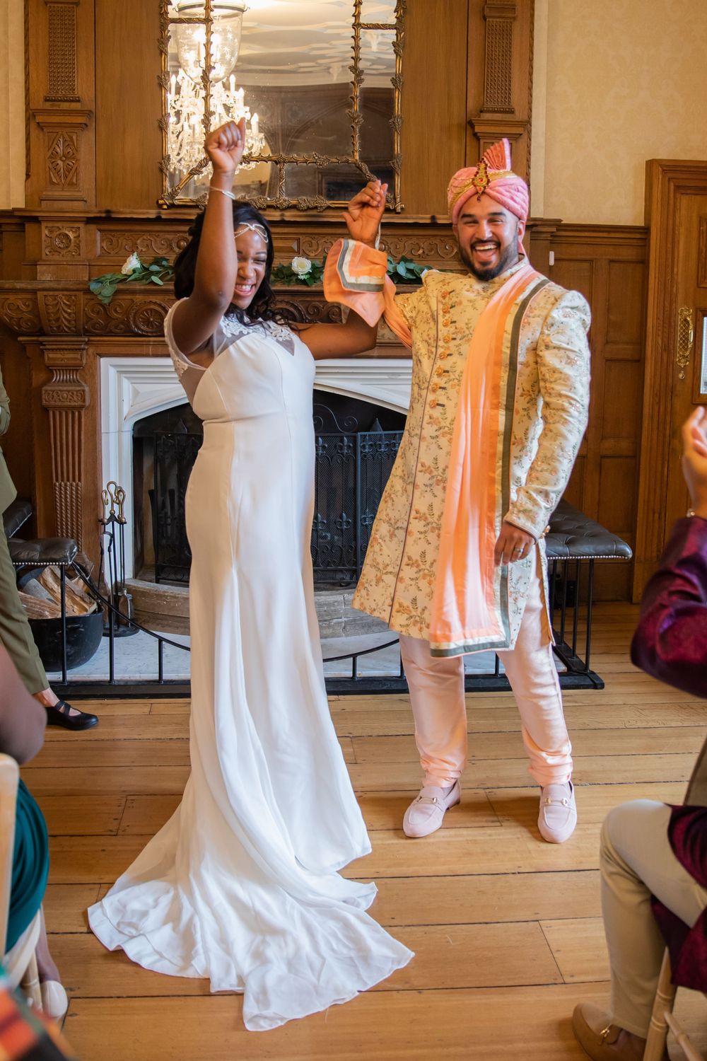 A joyful couple celebrates during their wedding ceremony in front of a fireplace.