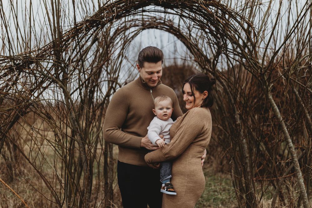 Candid family portrait captured beneath an archway of twisting winter branches.