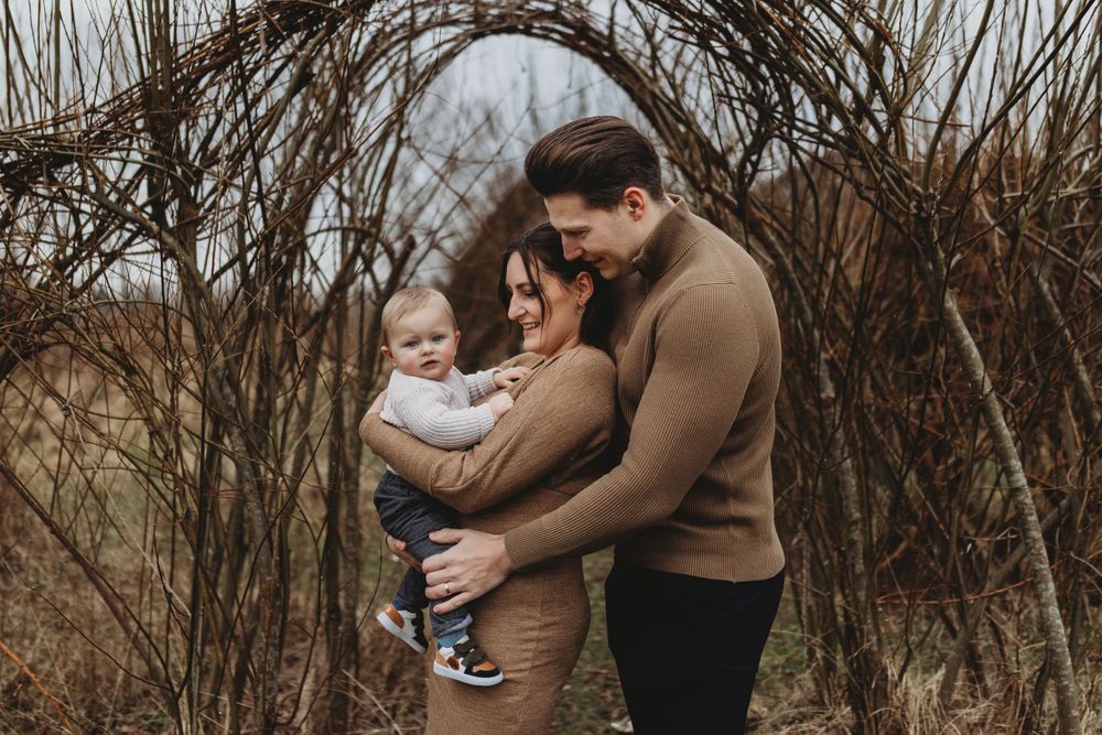 A tender family moment captured under bare winter branches in muted earth tones.