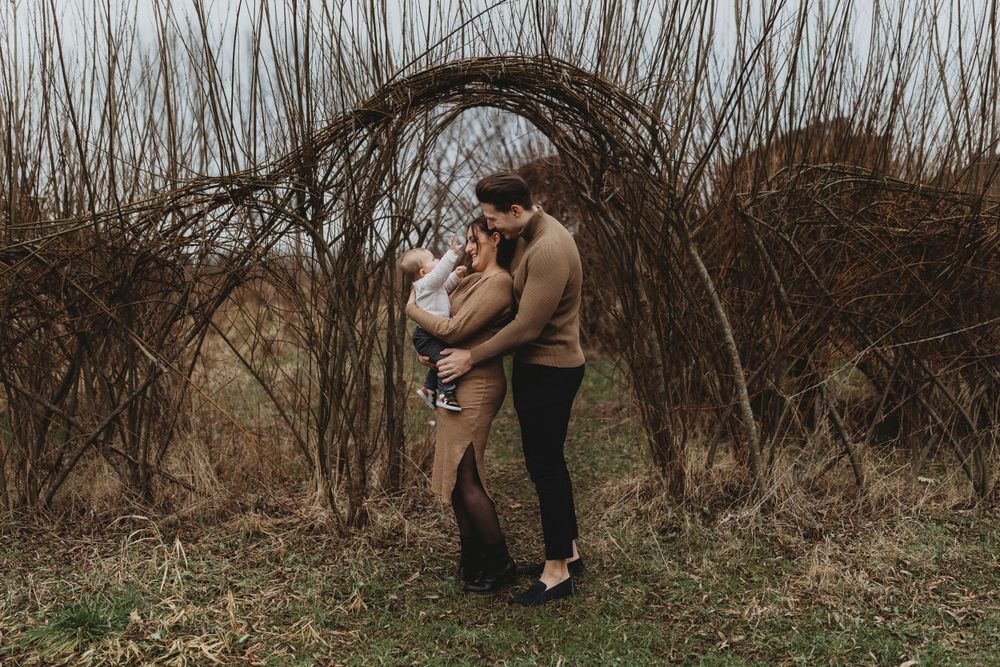 An intimate family portrait beneath an arched canopy of winter branches.