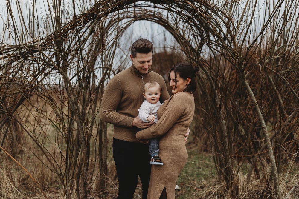 A loving embrace shared between family members under a natural arch of dried branches.