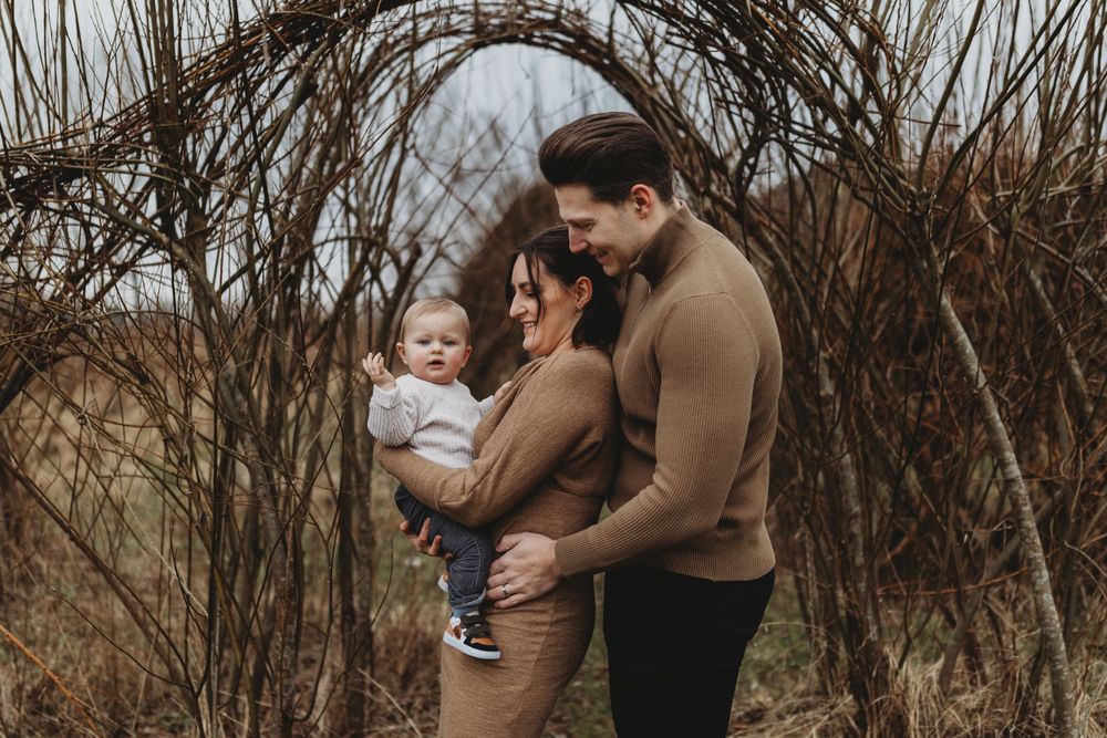 A sweet family moment captured in natural lighting under rustic twigs and branches.