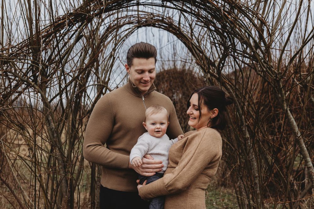 Candid family interaction captured under natural branch archway in warm autumn colors.
