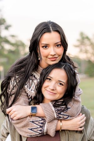 Two people wearing cozy sweaters embrace while enjoying a fall afternoon outdoors.