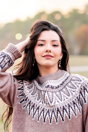 Person modeling a stylish Fair Isle pattern sweater in natural outdoor lighting.