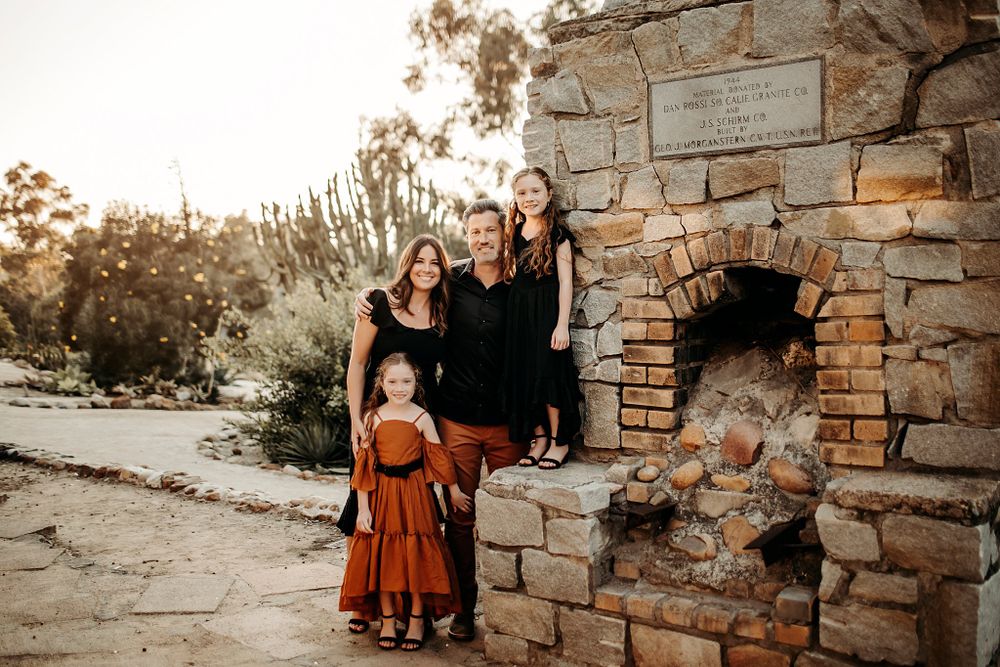 parents and girls gather on stone fireplace at cactus garden family session