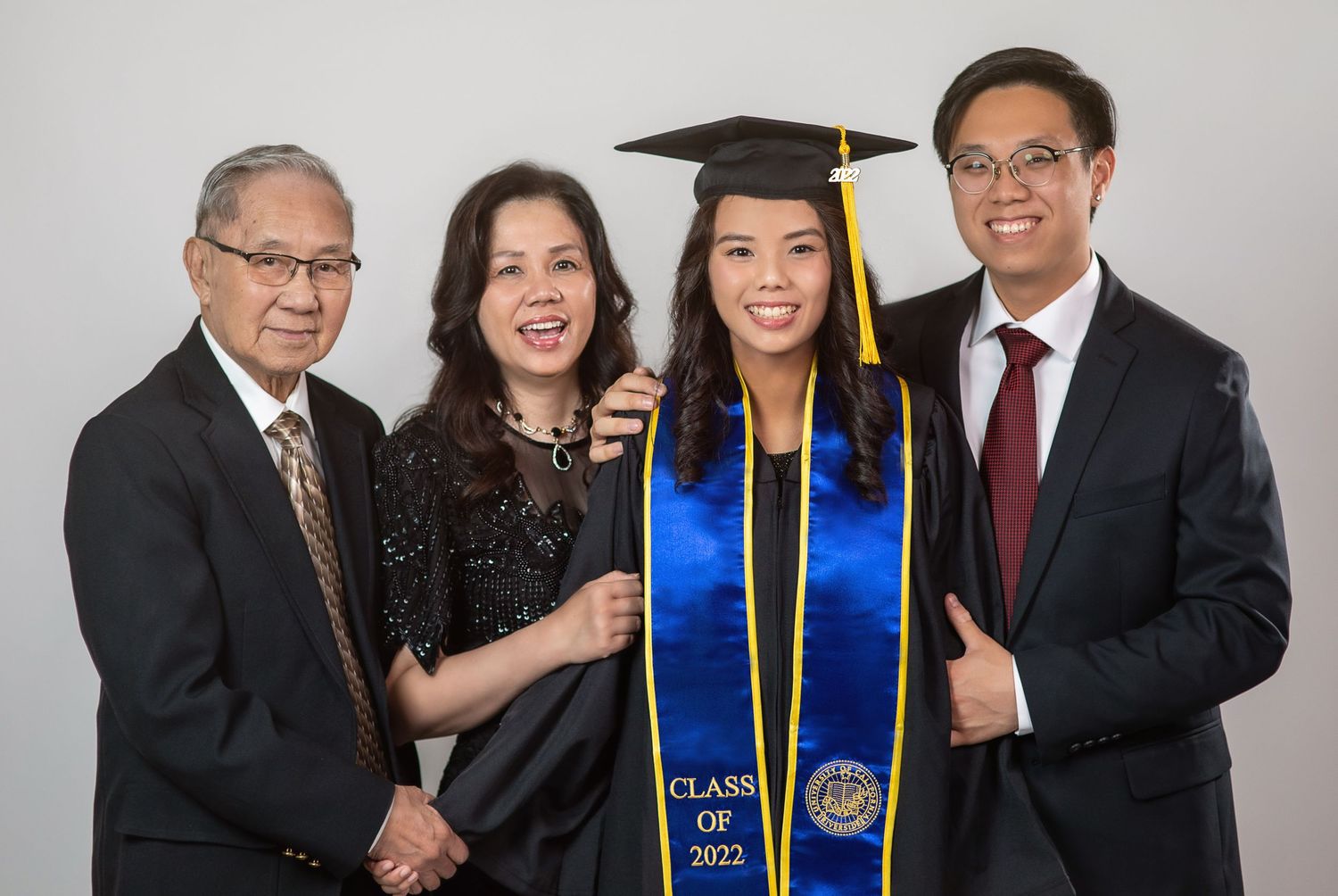 A formal graduation photo with academic regalia and stoles.